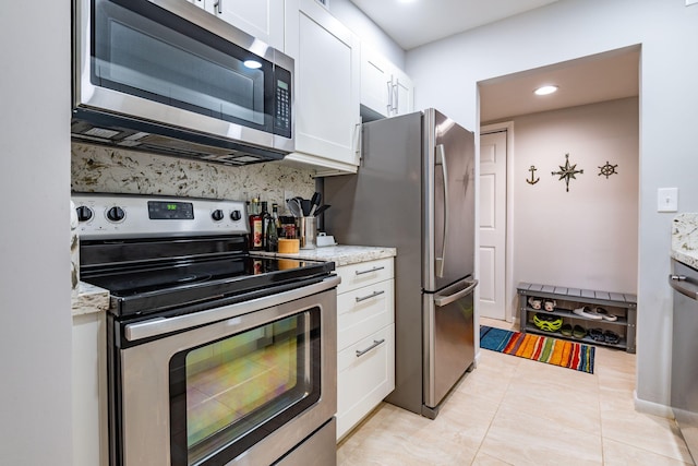 kitchen with light tile patterned flooring, light stone counters, white cabinetry, and appliances with stainless steel finishes