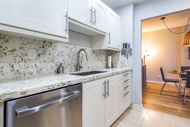 kitchen with decorative backsplash, white cabinets, stainless steel dishwasher, and sink