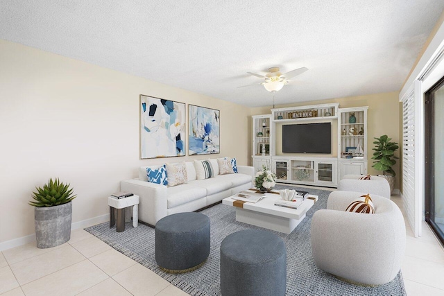 living room with a ceiling fan, tile patterned flooring, a textured ceiling, and baseboards