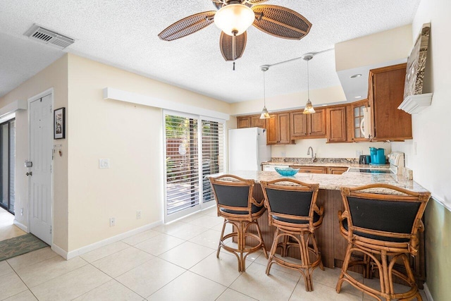 kitchen featuring kitchen peninsula, white appliances, ceiling fan, sink, and a breakfast bar area