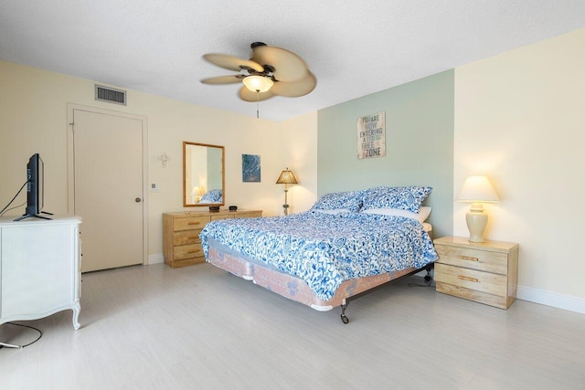 bedroom with ceiling fan, a textured ceiling, and hardwood / wood-style flooring