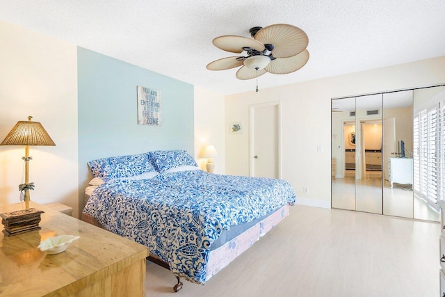 bedroom with light wood-type flooring, a textured ceiling, a closet, and ceiling fan