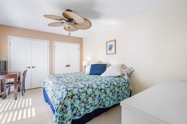 bedroom with ceiling fan, a textured ceiling, and multiple closets