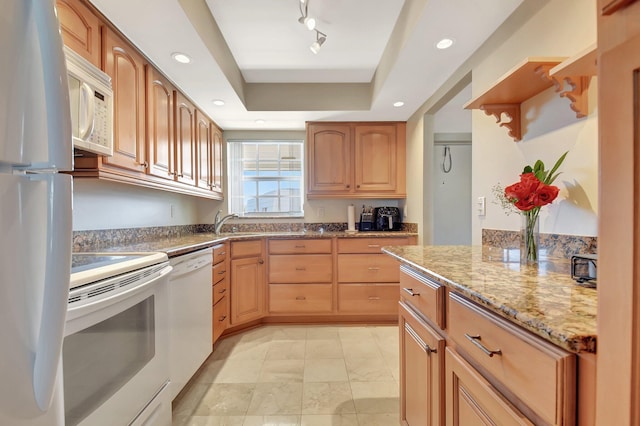 kitchen with a tray ceiling, white appliances, light stone countertops, and rail lighting