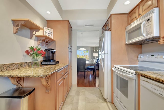 kitchen featuring light stone countertops and white appliances