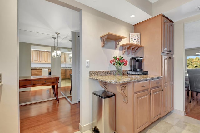 kitchen featuring pendant lighting, light stone countertops, and light hardwood / wood-style flooring