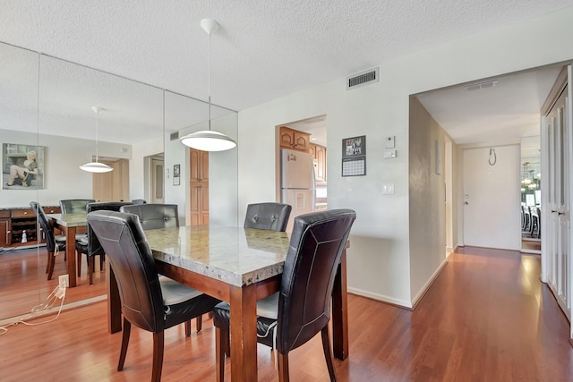 dining area with wood-type flooring and a textured ceiling