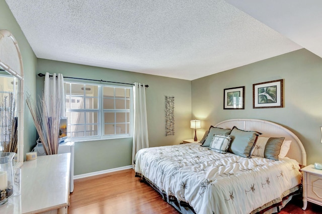 bedroom with light hardwood / wood-style flooring and a textured ceiling