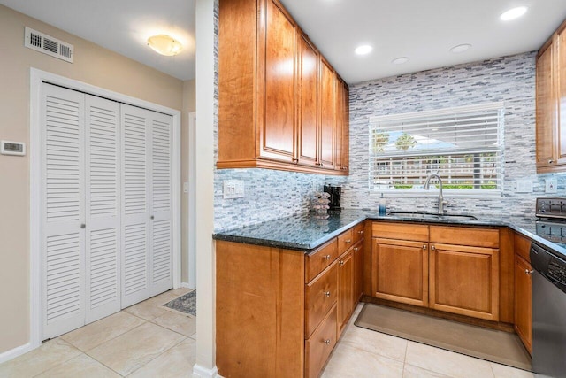 kitchen with decorative backsplash, sink, dark stone countertops, dishwasher, and light tile patterned flooring