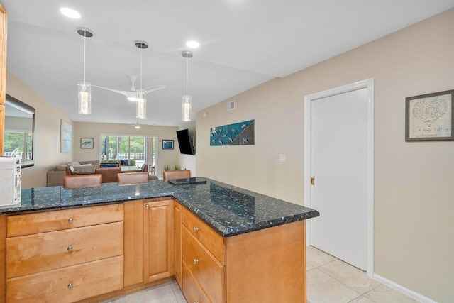 kitchen featuring ceiling fan, dark stone countertops, kitchen peninsula, pendant lighting, and light tile patterned floors