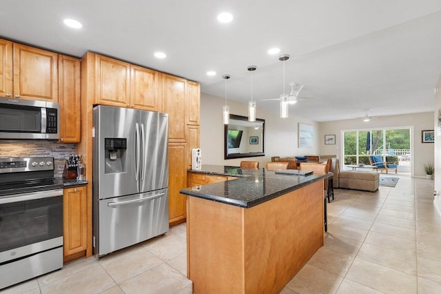 kitchen featuring ceiling fan, dark stone countertops, appliances with stainless steel finishes, decorative light fixtures, and light tile patterned flooring