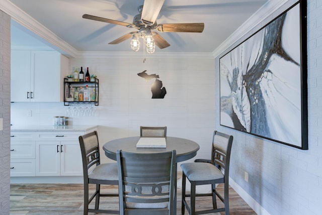 dining space featuring ceiling fan, light wood-type flooring, ornamental molding, and tile walls