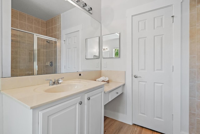 bathroom featuring wood-type flooring, an enclosed shower, vanity, and a textured ceiling