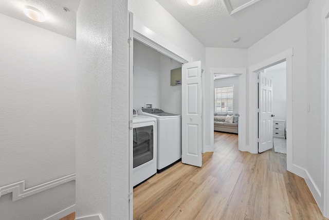 washroom featuring washing machine and dryer, washer hookup, light hardwood / wood-style floors, and a textured ceiling