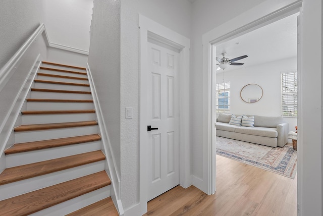 stairs featuring ceiling fan and light hardwood / wood-style floors