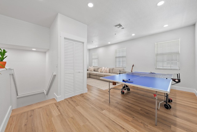 recreation room featuring light hardwood / wood-style flooring and a textured ceiling