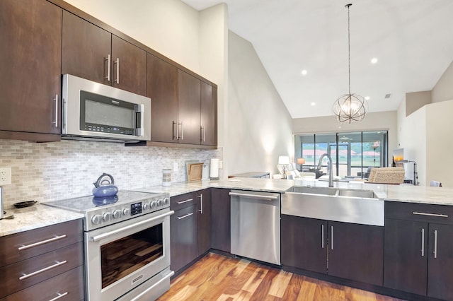 kitchen featuring a chandelier, decorative light fixtures, light hardwood / wood-style floors, vaulted ceiling, and appliances with stainless steel finishes