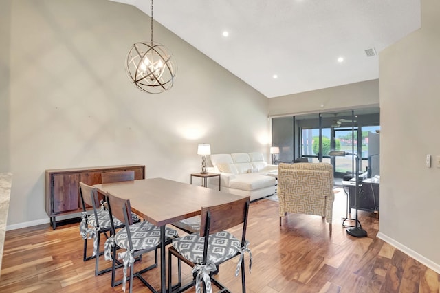 dining area featuring hardwood / wood-style floors, high vaulted ceiling, and a notable chandelier