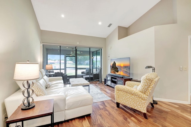 living room with light hardwood / wood-style floors and high vaulted ceiling