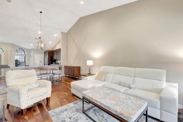 living room with sink, light hardwood / wood-style floors, vaulted ceiling, and an inviting chandelier