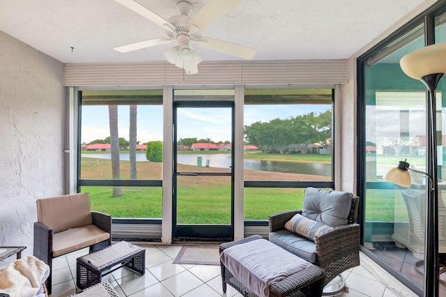 sunroom featuring ceiling fan and a water view