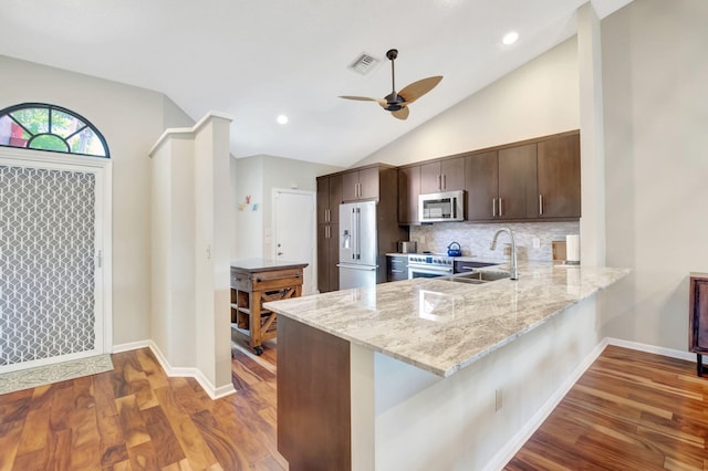 kitchen featuring kitchen peninsula, appliances with stainless steel finishes, dark hardwood / wood-style floors, and light stone countertops