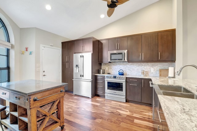 kitchen with lofted ceiling, light hardwood / wood-style flooring, light stone countertops, appliances with stainless steel finishes, and dark brown cabinetry