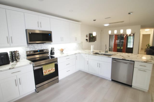 kitchen with white cabinets, sink, decorative light fixtures, kitchen peninsula, and stainless steel appliances