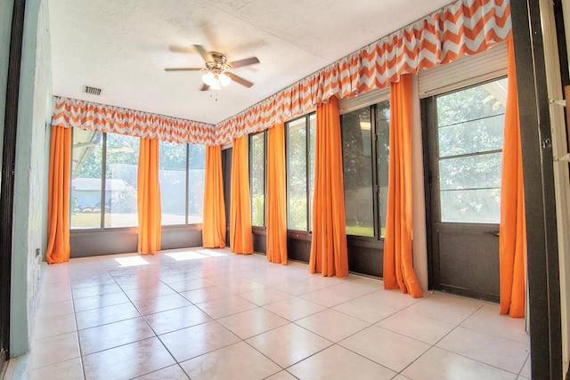 unfurnished room featuring a wealth of natural light, light tile patterned flooring, and ceiling fan