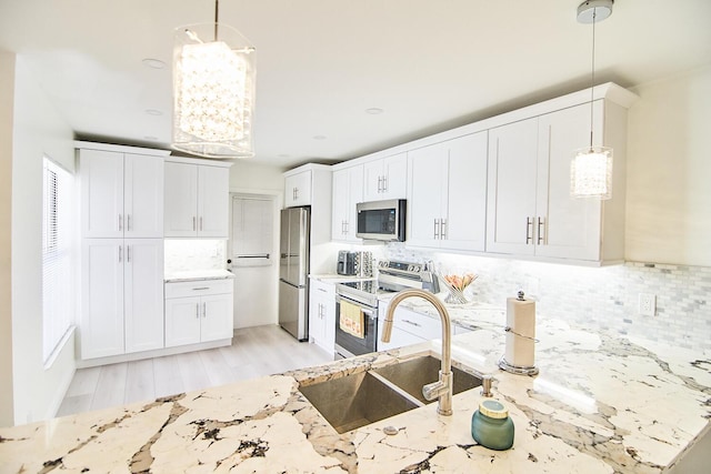 kitchen featuring decorative light fixtures, stainless steel appliances, light hardwood / wood-style floors, and sink