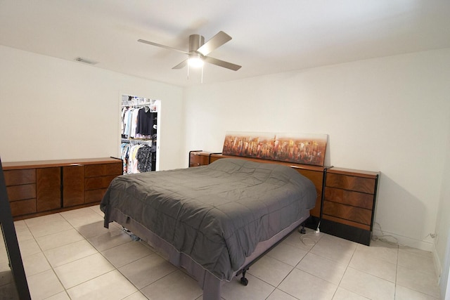 bedroom featuring ceiling fan, a walk in closet, light tile patterned floors, and a closet