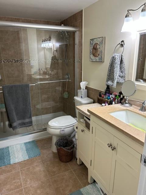 bathroom with an enclosed shower, tile flooring, vanity, and toilet