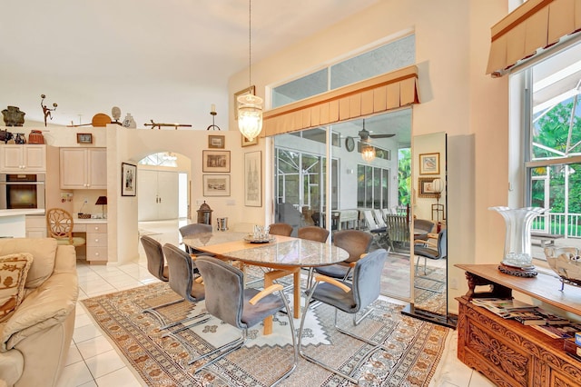 tiled dining space with a high ceiling and ceiling fan