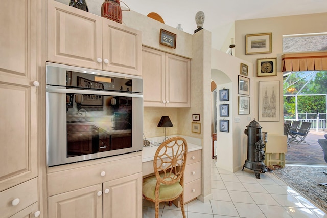 kitchen featuring oven, light tile patterned flooring, and built in desk