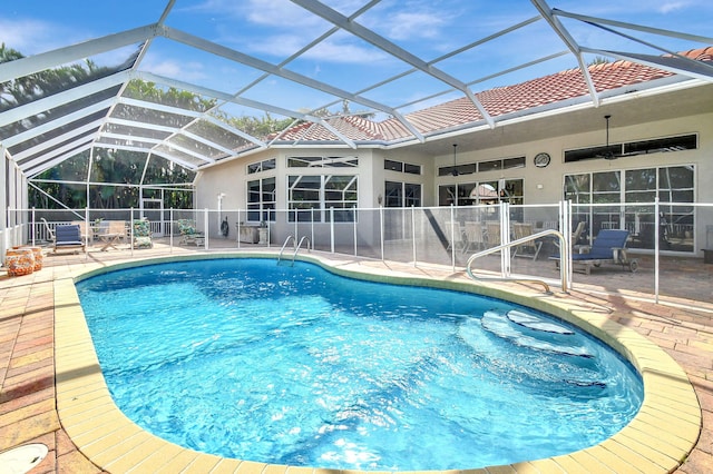 view of pool with a patio area, glass enclosure, and ceiling fan