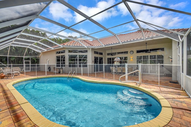 view of swimming pool with ceiling fan, glass enclosure, and a patio area