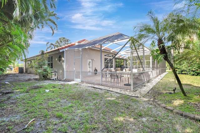 rear view of house featuring a swimming pool, a patio area, a lawn, and a lanai