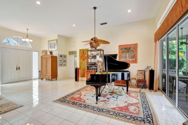 tiled foyer with a towering ceiling and ceiling fan with notable chandelier