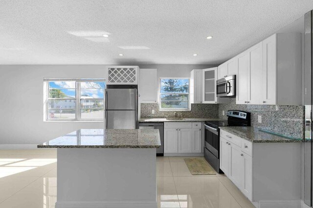 kitchen with appliances with stainless steel finishes, a healthy amount of sunlight, and tasteful backsplash