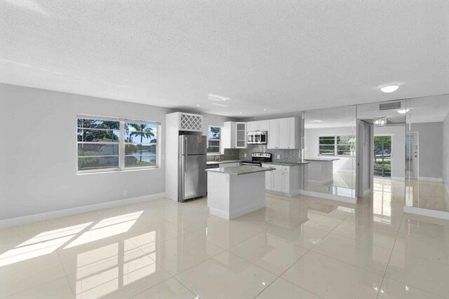 kitchen with stainless steel appliances, white cabinetry, tasteful backsplash, and a healthy amount of sunlight