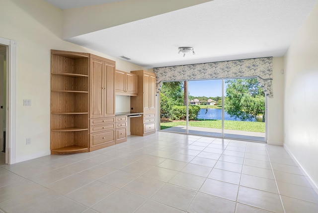 tiled spare room featuring a water view and a textured ceiling