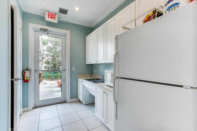 kitchen with light tile patterned flooring, white refrigerator, white cabinets, ornamental molding, and sink