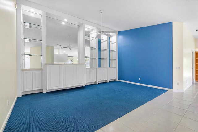 unfurnished room with light carpet, ceiling fan, and a towering ceiling