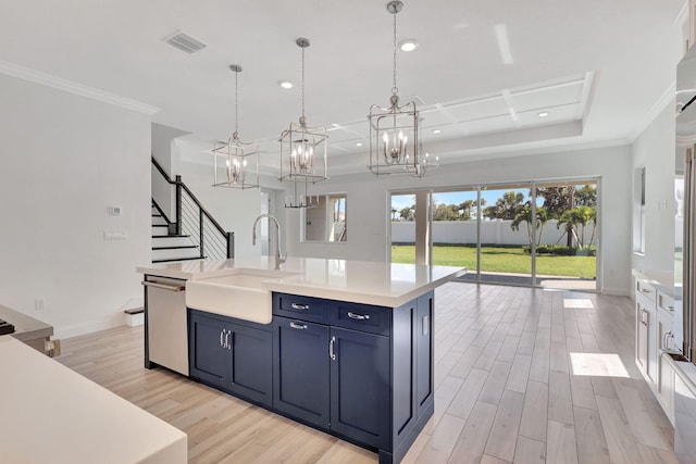 kitchen featuring a center island with sink, light countertops, hanging light fixtures, a sink, and dishwasher