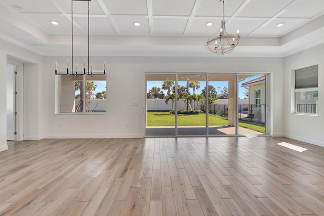 unfurnished dining area with a chandelier, light wood-type flooring, coffered ceiling, and a healthy amount of sunlight