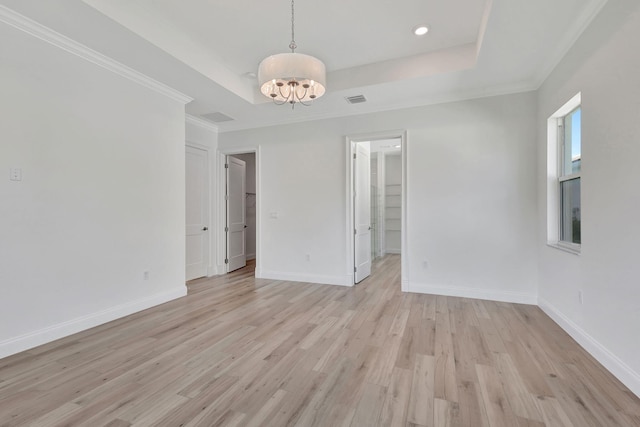 unfurnished room with baseboards, a tray ceiling, visible vents, and light wood-style floors