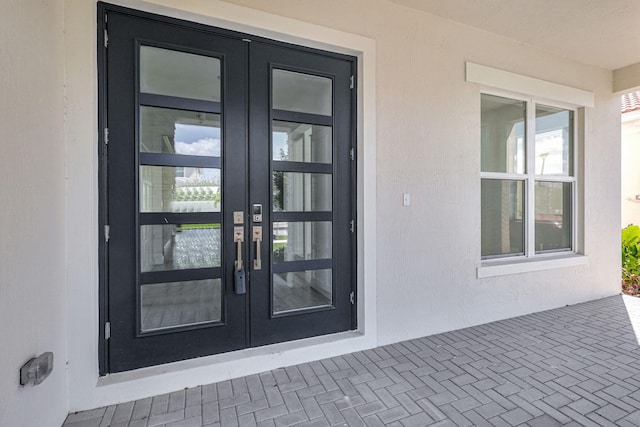 view of exterior entry featuring french doors and stucco siding