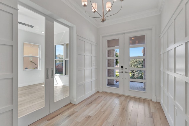 doorway with light wood-style floors, ornamental molding, a decorative wall, and french doors