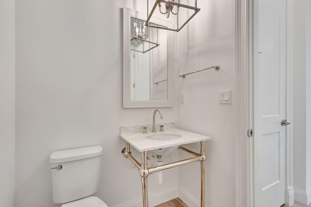 half bathroom featuring a sink, toilet, and baseboards