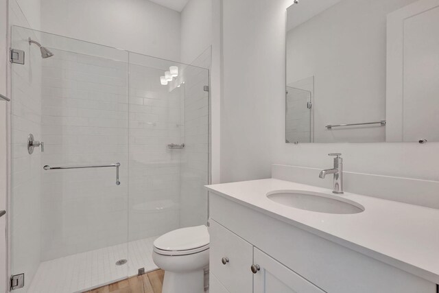 full bath with toilet, a shower stall, wood finished floors, and vanity